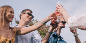 Grupo de personas brindando con vino rosado en un evento de empresa al aire libre