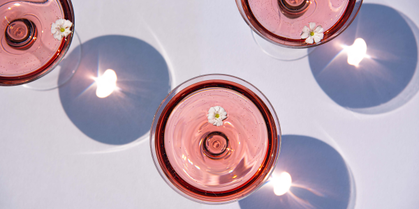 Copas de vino rosado con flor decorativa, detalle elegante para eventos de verano corporativos